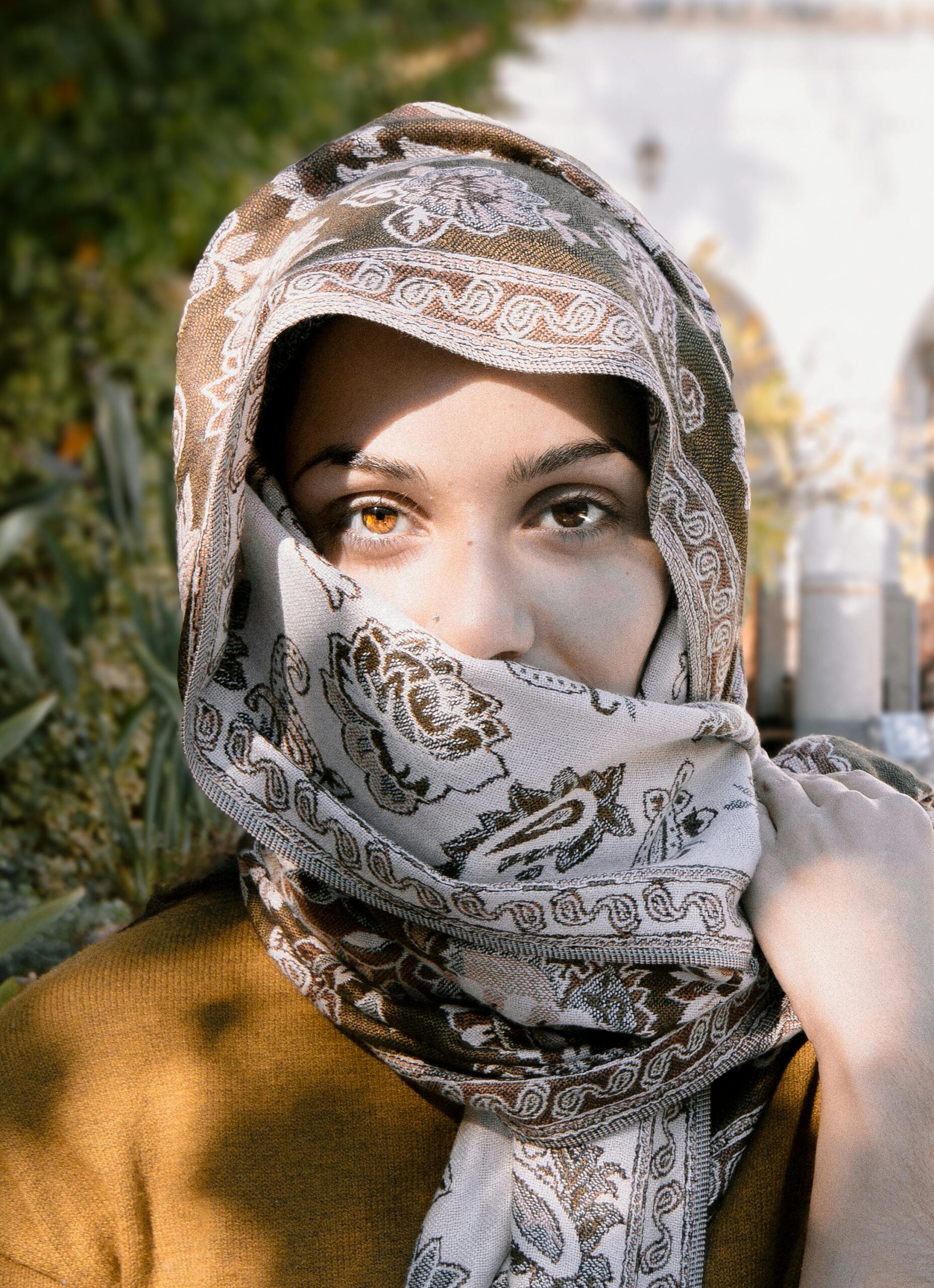Close-up portrait of a woman wearing an ornate headscarf, showcasing her expressive eyes.